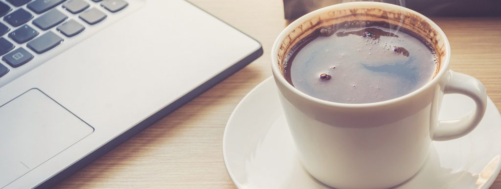 Coffee cup on office desk next to laptop