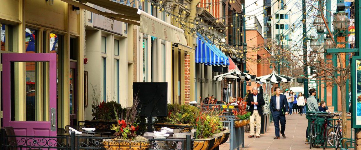 People walking down steet in front of various restaurants